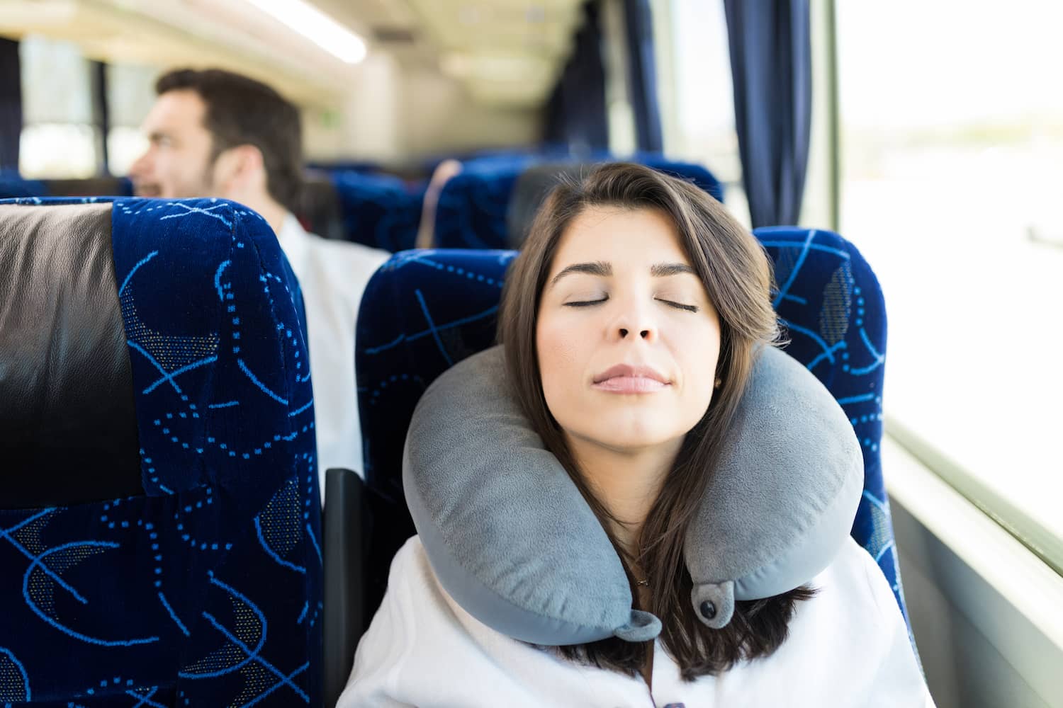 Ein Gast sitzt entspannt mit Nackenhörnchen im Bus und hat die Augen geschlossen